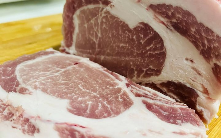 หมูสันนอกก้อนใหญ่มีชั้นมันและไขมันแทรก วางบนโต๊ะเตรียมอาหาร